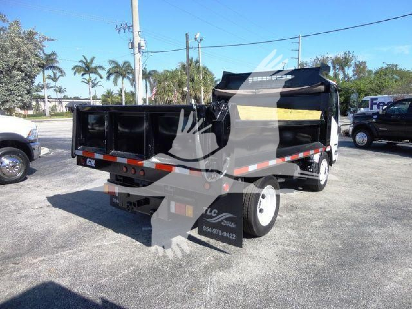 Isuzu NPR HD dump truck in a lot showing dump bed and rear view with taillights and bumper.