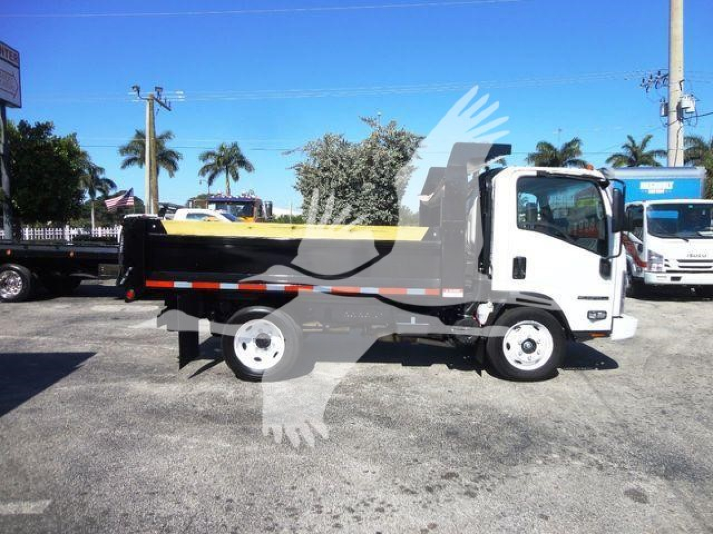 Isuzu NPR-HD dump truck side view showing dumping bed and cab with white exterior.