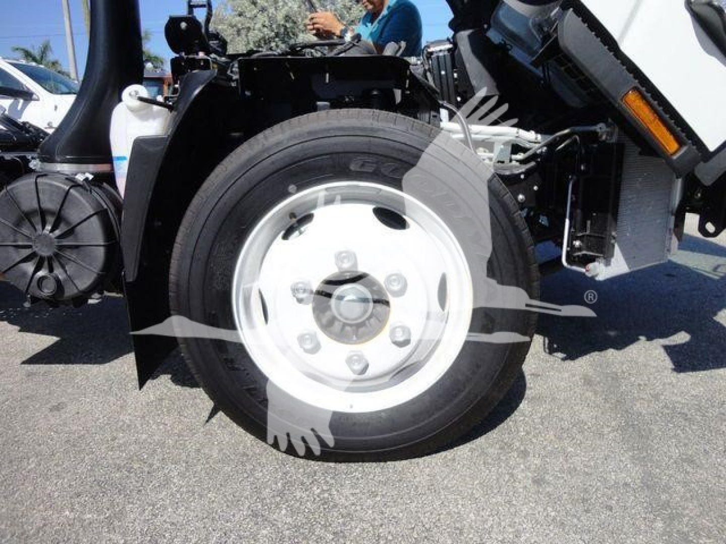 Isuzu NPR-HD dump truck front wheel assembly with white steel wheel and black tire, visible suspension and chassis components.