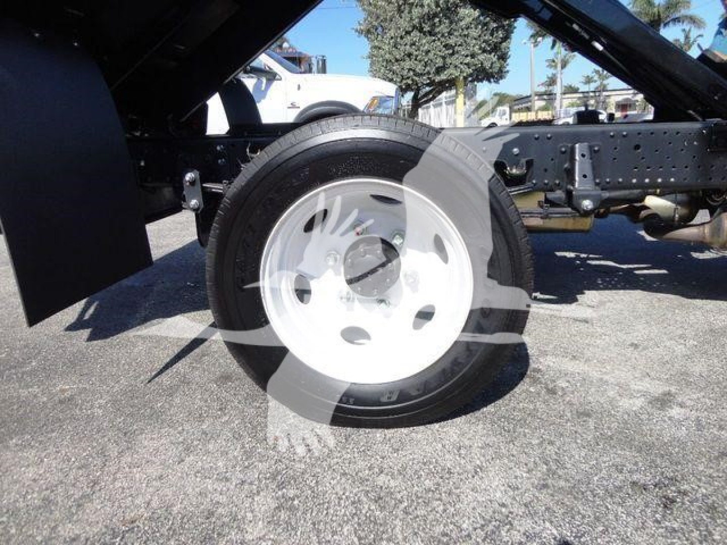 Isuzu NPR HD truck chassis showing front wheel and suspension with white steel wheel and black tire in side view.