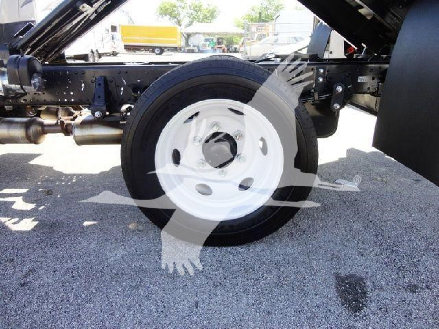 Isuzu NPR-HD truck chassis rear wheel and suspension visible, with spare tire/rim and undercarriage components.