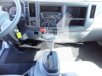 Isuzu NPR dashboard and gear shifter view in cab interior showing steering wheel, center console, and gauge cluster.