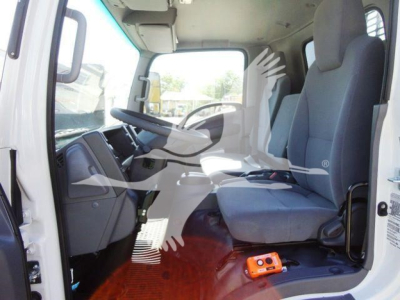 Isuzu NPR HD commercial truck cab interior with driver and passenger seats, steering wheel, dashboard, and a small orange device on the floor.