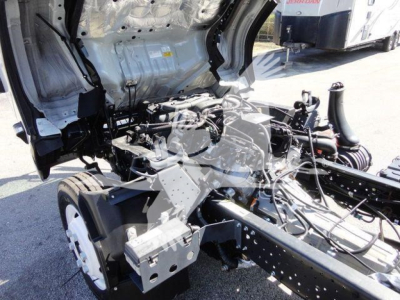 Isuzu NPR HD chassis and cab area showing engine bay with exposed components and wiring; dump truck configuration under construction.