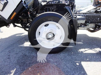 Isuzu NPR-HD truck front wheel and suspension showing white steel wheel and tire, partial chassis, and hydraulic lines.