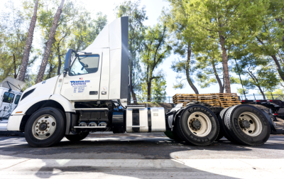 Volvo VNR truck side view showing cab and chassis with fuel tanks and wheels; some text on door panel including company logo