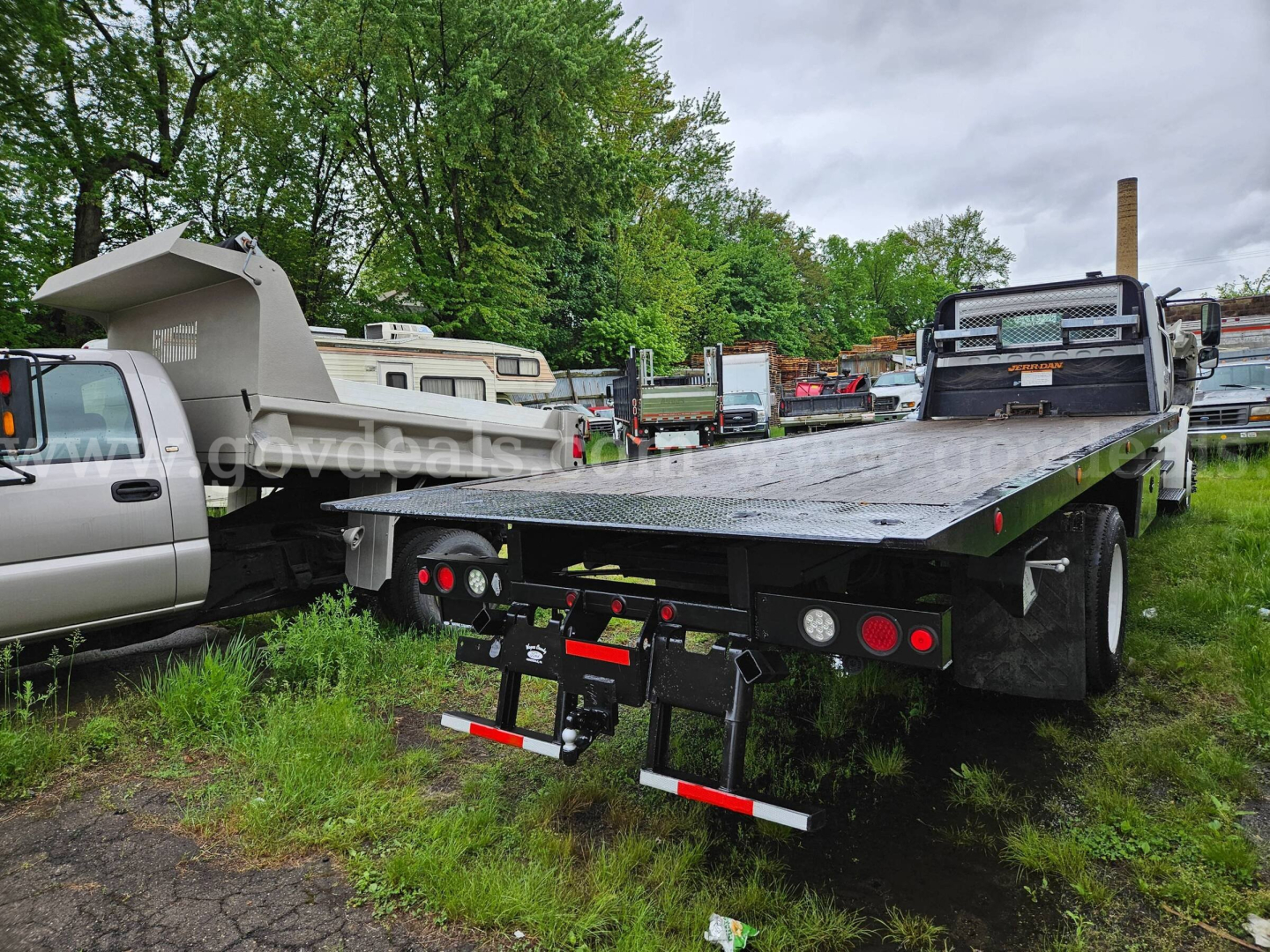 Flatbed tow truck bed on a Freightliner M2 106 with rear dual taillights and bumper, equipment on trailer, VIN/stock info not visible on the image.