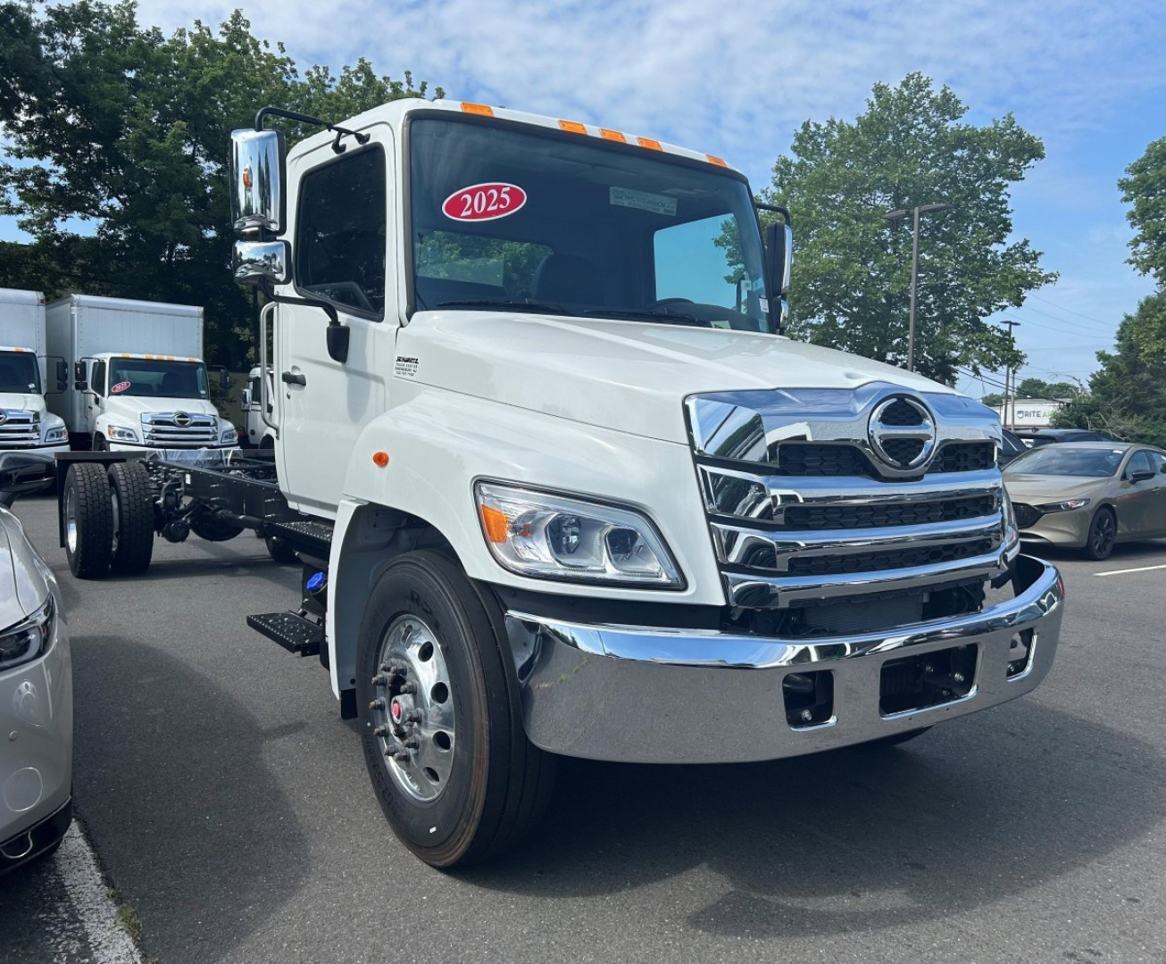 Hino L6 tow truck front view showing chrome grille, headlights, and bumper with 2025 sticker on windshield.