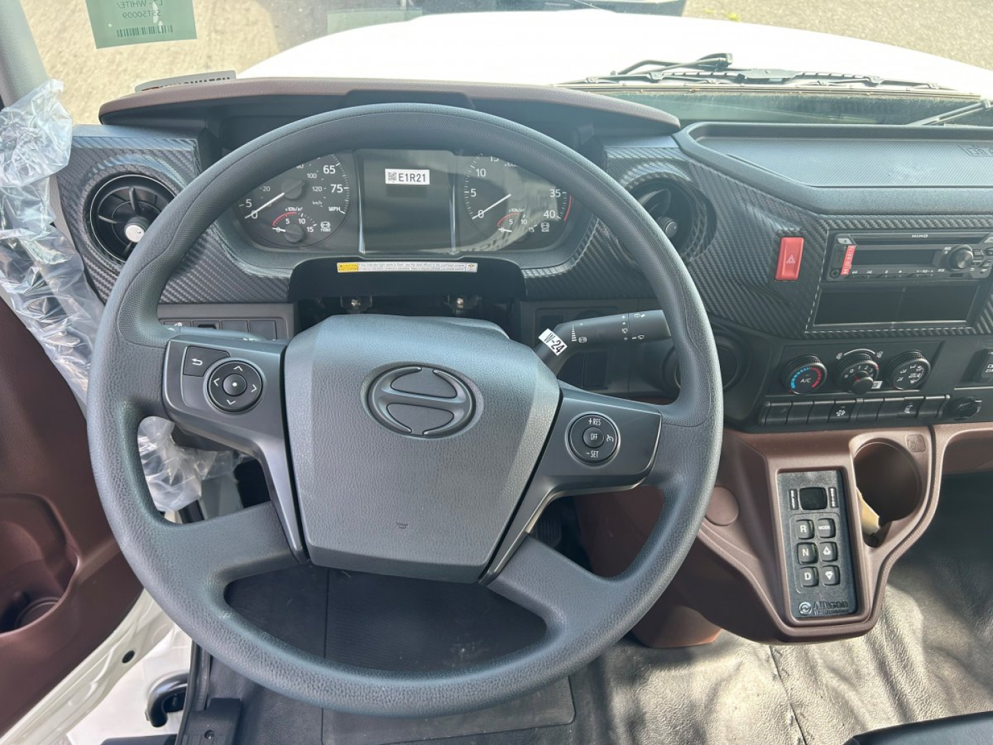 Dashboard and steering wheel of a 2025 Hino L6 tow truck interior showing steering wheel and instrument cluster with center console and controls