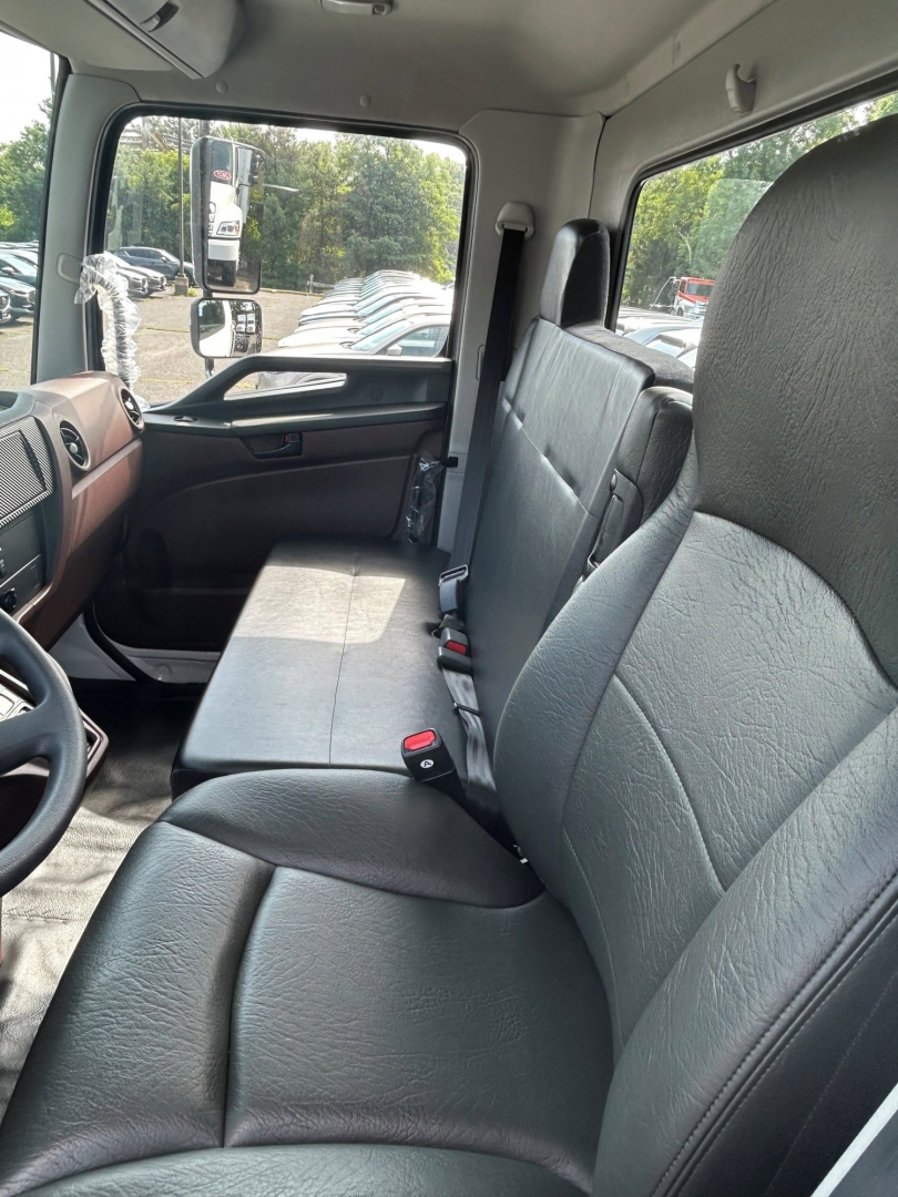 Cab interior of a 2025 Hino L6 truck showing front bench seat and dashboard with steering wheel, gray fabric seats, and door panel.