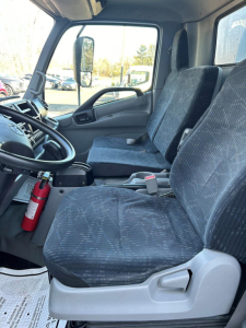 Hino 155 cab interior showing driver and passenger seats with steering wheel and dashboard.