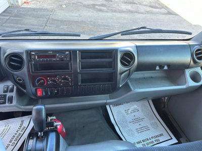 Dashboard of a Hino box truck interior showing steering column, steering wheel, climate controls, radio, vents, and glove compartment.
