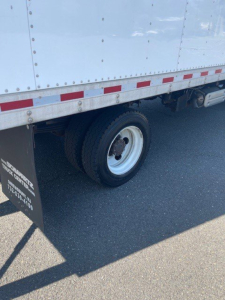 Truck wheel area of a 2018 Hino 155 box truck showing a single rear wheel and mudflap with small white text