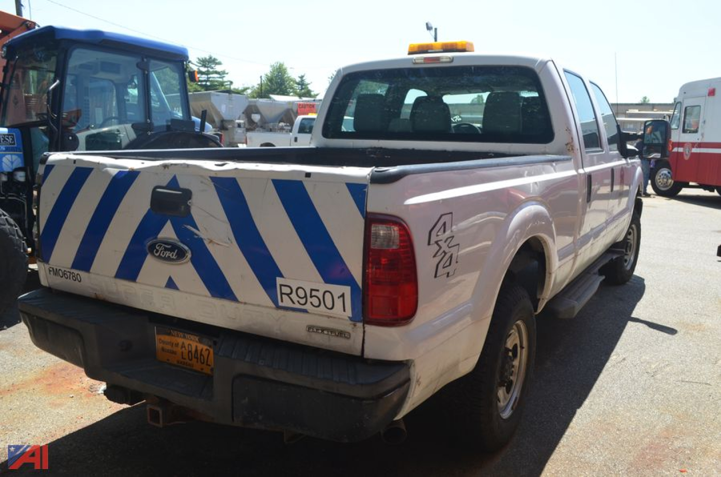 Ford F-250 Super Duty pickup truck rear view with blue and white striped tailgate, R9501 placard, and emergency beacon on cab.