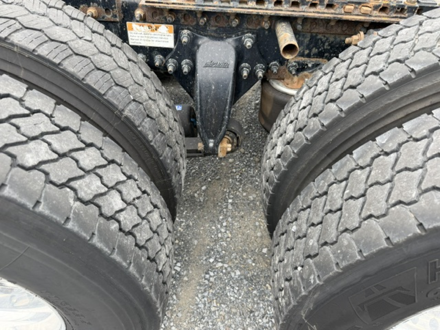 Freightliner Cascadia CA125DC undercarriage showing tandem drive axles and suspension components between dual rear wheels.