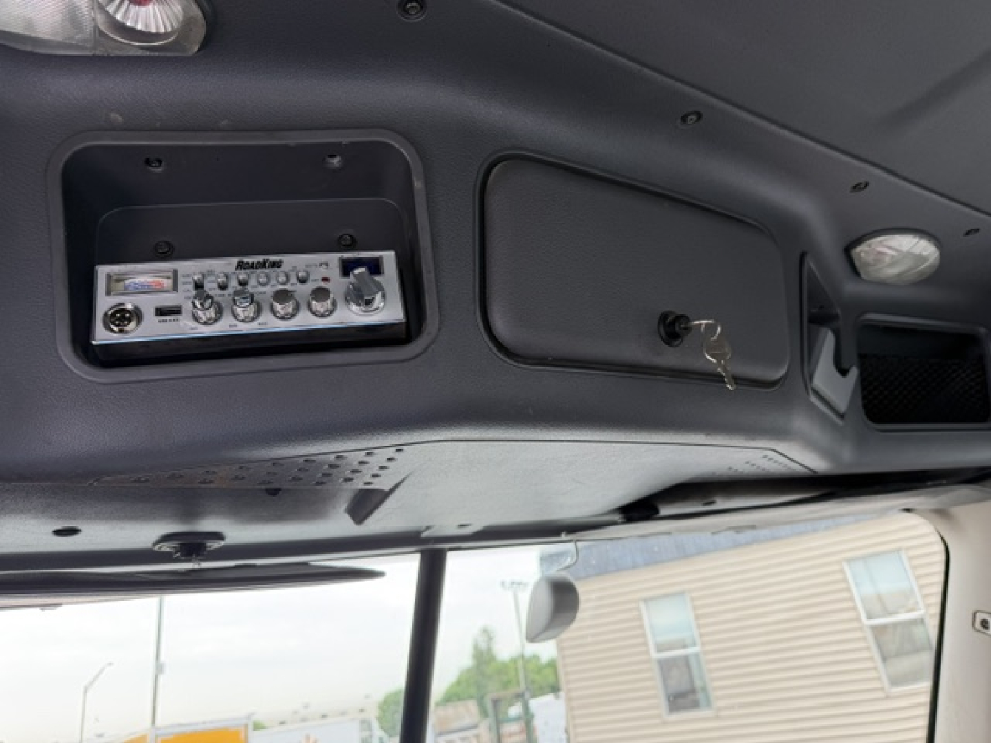 Dashboard interior showing radio panel and overhead console in Freightliner Cascadia cab with keys in ignition.