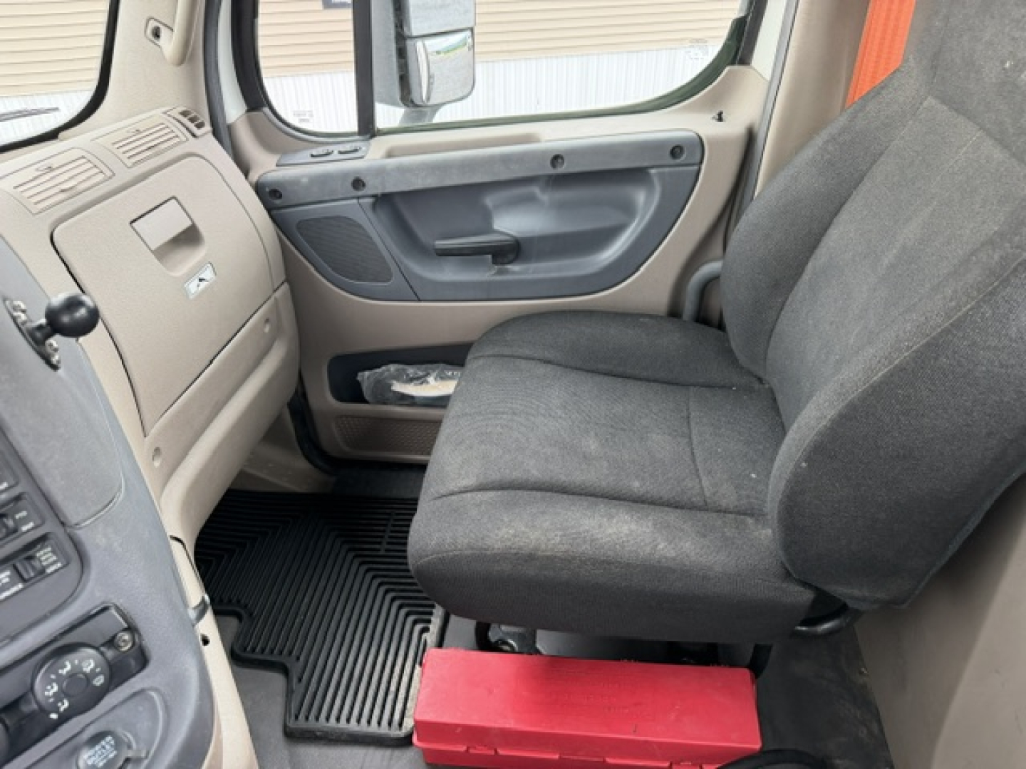 Freightliner Cascadia cab interior showing front passenger seat and dashboard area with door panel and floor mat.