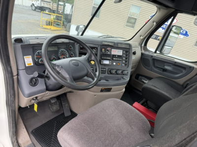 Cab interior of a Freightliner Cascadia CA125DC showing steering wheel, dashboard gauges, control panel, and driver's seat.