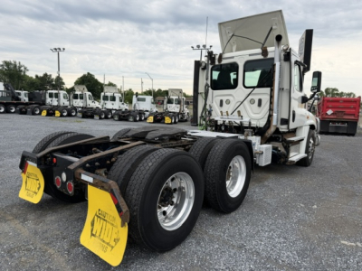 Freightliner Cascadia CA125DC tractor rear view showing dual rear axles, fifth wheel, and yellow caution mud flaps