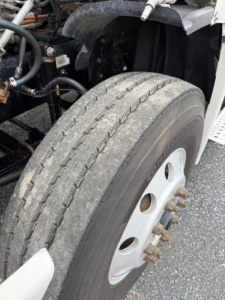 Freightliner Cascadia CA125DC front wheel and tire with exposed components and engine bay in view.