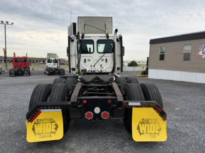 Truck chassis rear view showing fifth wheel area and yellow mud flaps with CAUTION WIDE TURNS markings.