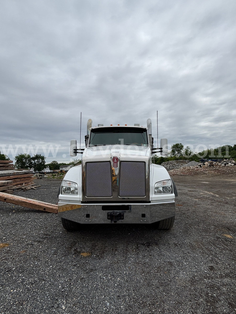 Front view of a white 2016 Kenworth T880 roll-off truck showing grille, bumper, and headlights with large chrome bumper and Kenworth emblem.