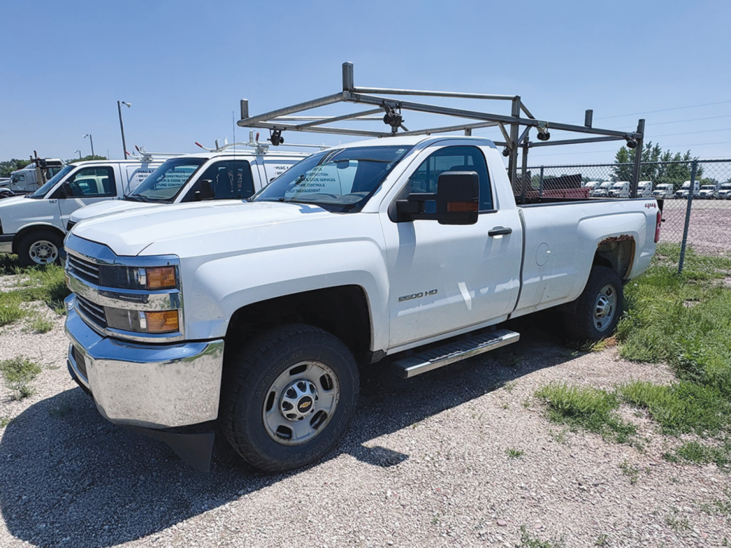Chevrolet Silverado 2500HD pickup truck in white, extended cab, 4x4 with ladder rack and side step visible.