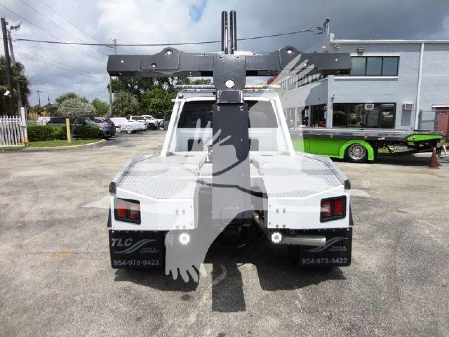 Backing view of a white 2024 Ram 4500 with a heavy-duty crane/winch mount and dual rear taillights. Vehicle details not fully legible from distance.
