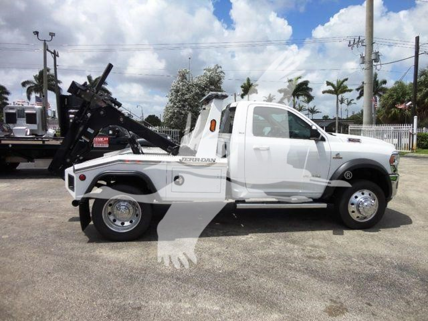 Ram 4500 tow truck side view with white cab and black winch mechanism, lettering on side shows Ram 4500, wheel covers, two-tone tires, chrome step rails.