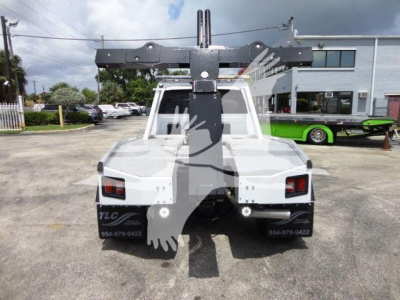 Backing view of a white 2024 Ram 4500 with a heavy-duty crane/winch mount and dual rear taillights. Vehicle details not fully legible from distance.