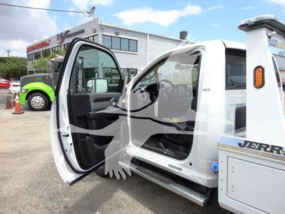 Ram 4500 SLT truck cab interior with front door open showing steering wheel and dashboard; exterior white body with Jerry Dismount winch equipment on side in background.
