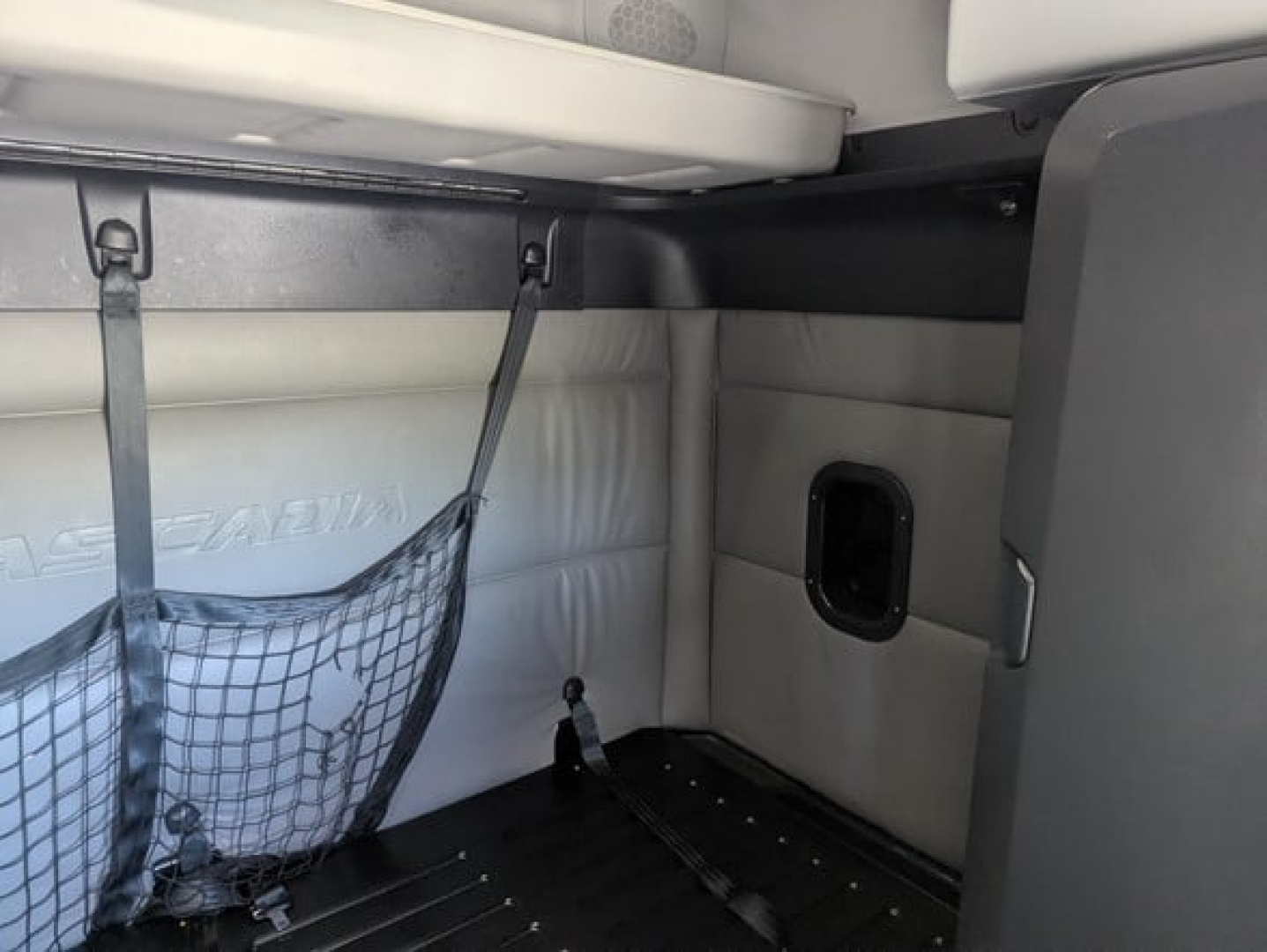 Freightliner Cascadia cab interior showing sleeper area with storage net and side panel.