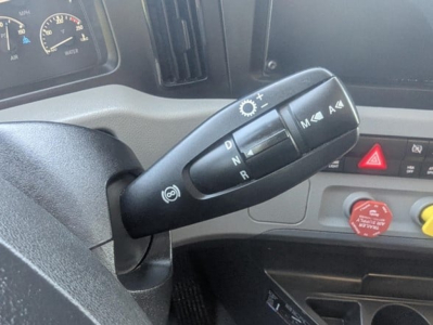 Cab interior showing steering column stalk with gear selector, dashboard gauges, red hazard button, and red circular cap; part of a 2022 Freightliner Cascadia 126 truck.
