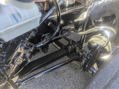 Freightliner Cascadia 126 chassis and front axle components visible in the engine bay area with hoses and metal framework.