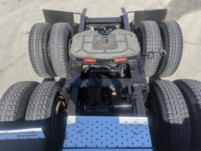 Truck chassis with fifth wheel and dual rear axles visible; platform shows perforated metal step and suspension components.