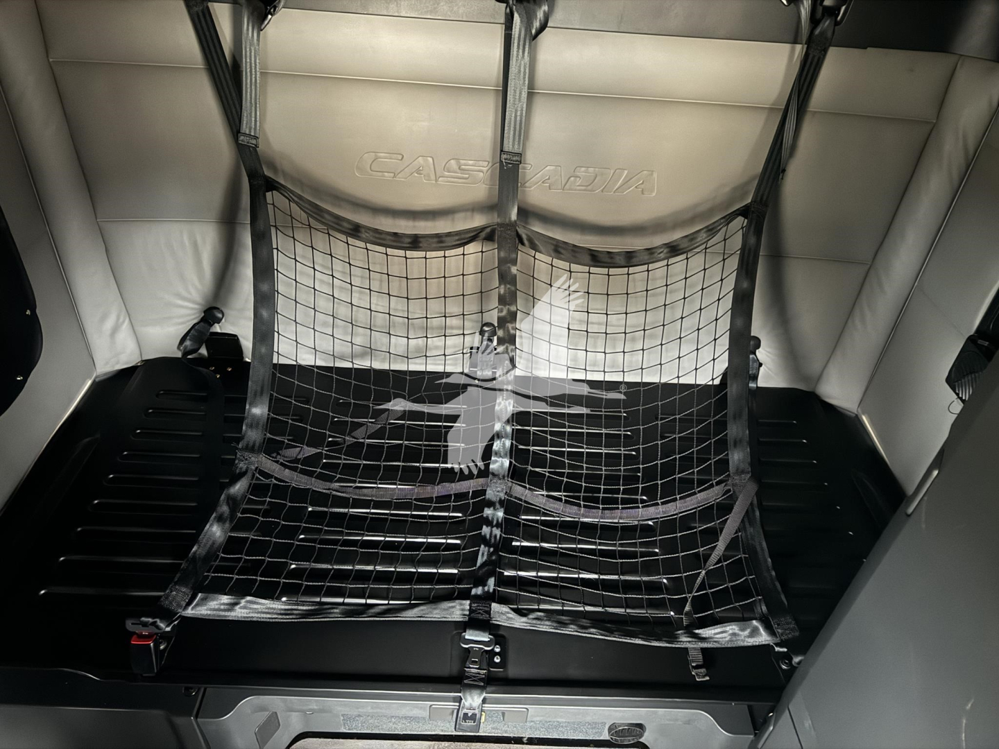 Freightliner Cascadia 126 sleeper cab interior showing cargo net over floor and Casadia embossed panel.