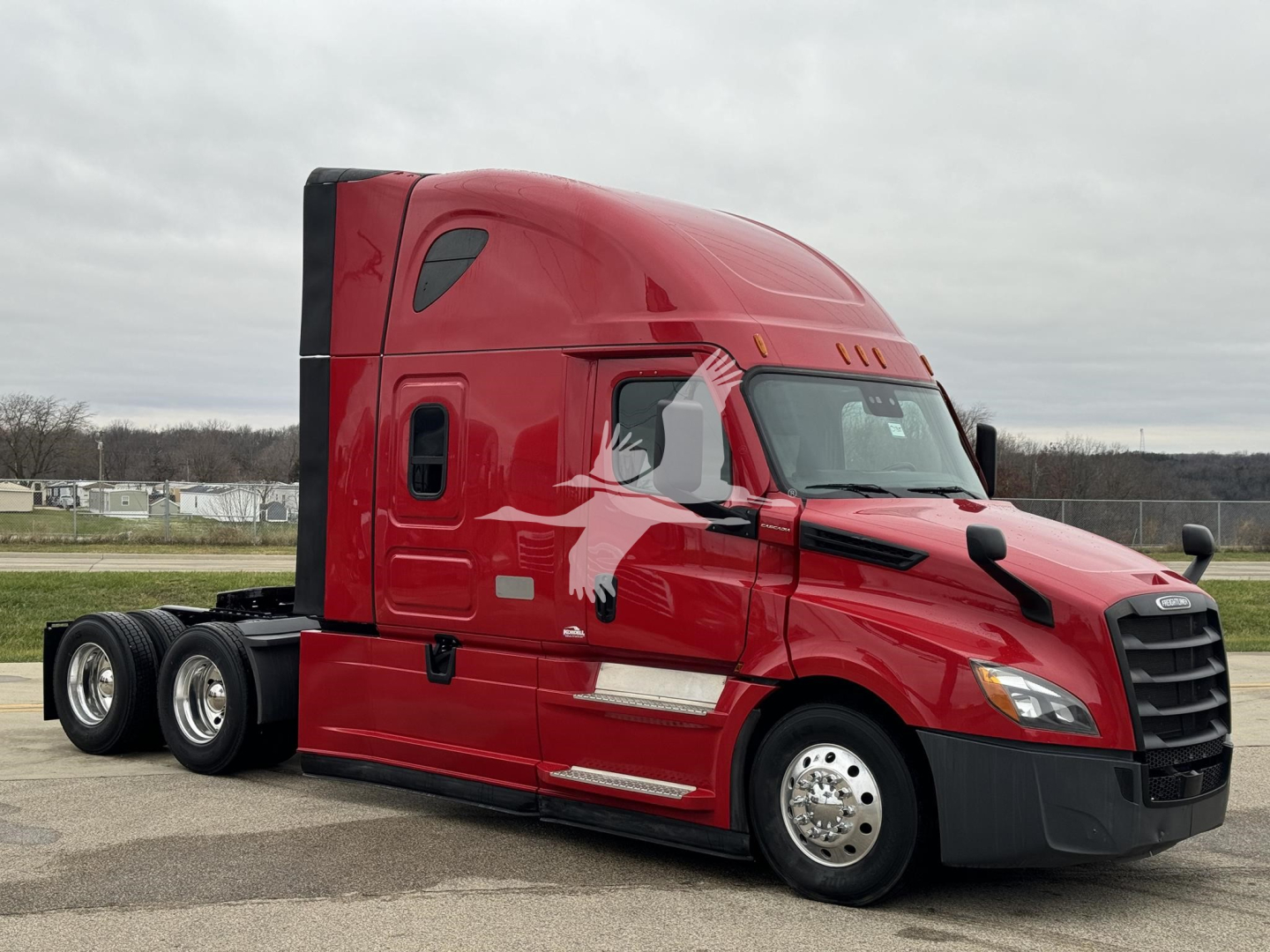 Red Freightliner Cascadia 126 tractor with sleeper cab, side view showing aerodynamic mirrors and third axle, no visible text on truck.