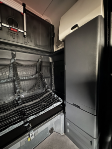Cabin sleeper area of a 2023 Freightliner Cascadia 126 showing storage nets, cabinet doors, and side panel with compartments.