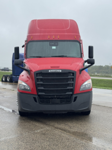 Truck front view of a red 2023 Freightliner Cascadia 126 sleeper cab showing grille, headlights, and bumper.