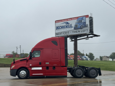 Freightliner Cascadia 126 sleeper tractor with red cab and billboard trailer hardware visible.