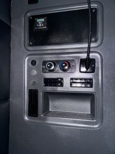 Freightliner Cascadia dash panel showing HVAC controls, storage pocket, and 12V power outlet.