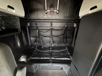 Freightliner Cascadia sleeper cab interior showing storage net with mesh, cargo area, and overhead panels; cabin light and tie-downs visible.