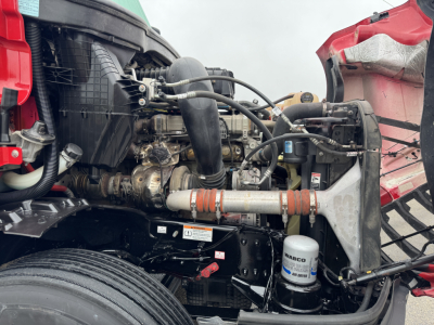 Engine bay of a Freightliner Cascadia 126 with visible hoses, air intake, coolant reservoir, and oil filter; components and piping labeled but no legible text readable.