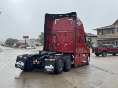 Truck chassis and rear of a red Freightliner Cascadia 126 tractor, view from the left-rear showing rear wheels and mudflaps with Kordell trailer dealership text.