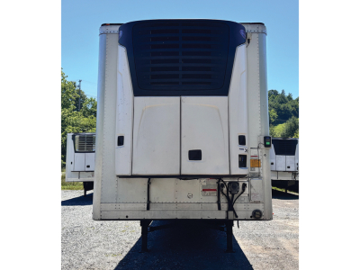 Rear view of a 2024 Utility 3000R trailer with a white curbside wall, dark blue refrigeration unit, and lower access doors. Central axles and landing gear visible.
