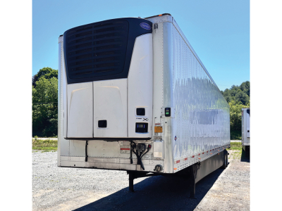 Utility 3000R refrigerated trailer with rear refrigeration unit and white body, dock bumper, blue sky background, on gravel lot.