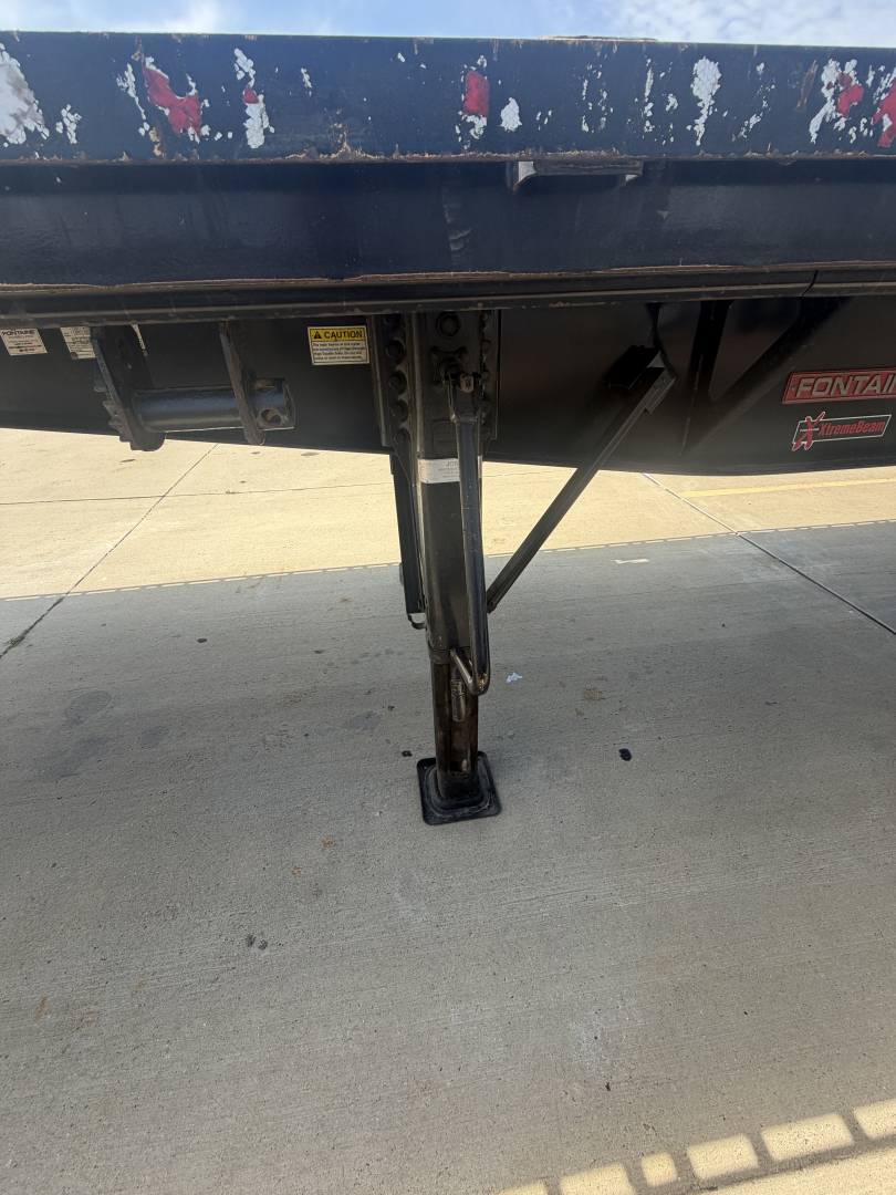 Trailer landing gear and underside of Fontaine flatbed trailer showing support leg and hydraulic or manual crank with steel frame