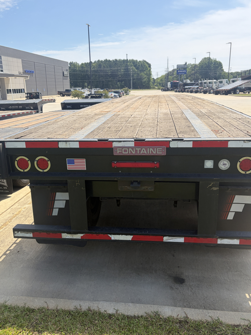 Flatbed trailer rear view showing Fontaine HAVSF12SST branding and taillights, with wooden deck and bumper stripes.