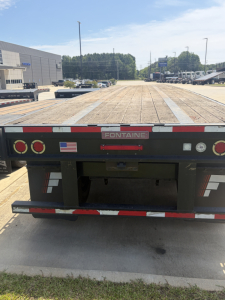 Flatbed trailer rear view showing Fontaine HAVSF12SST branding and taillights, with wooden deck and bumper stripes.
