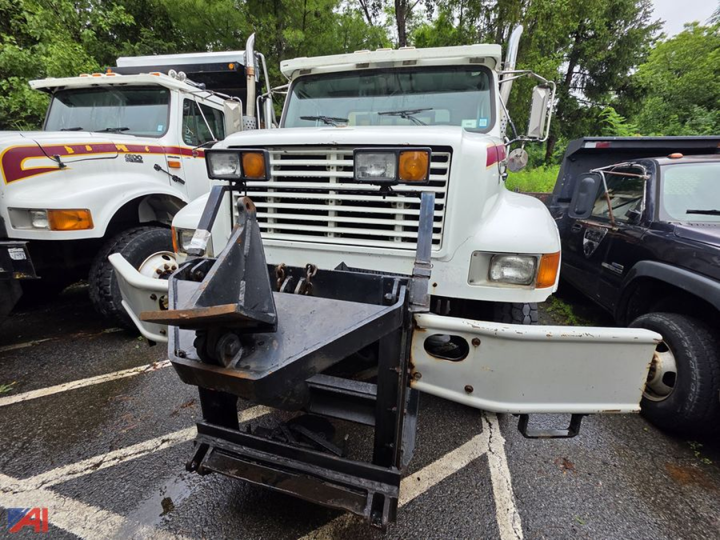 Dump truck in-service showing front view with a heavy front hitch/loader attachment and large grille.